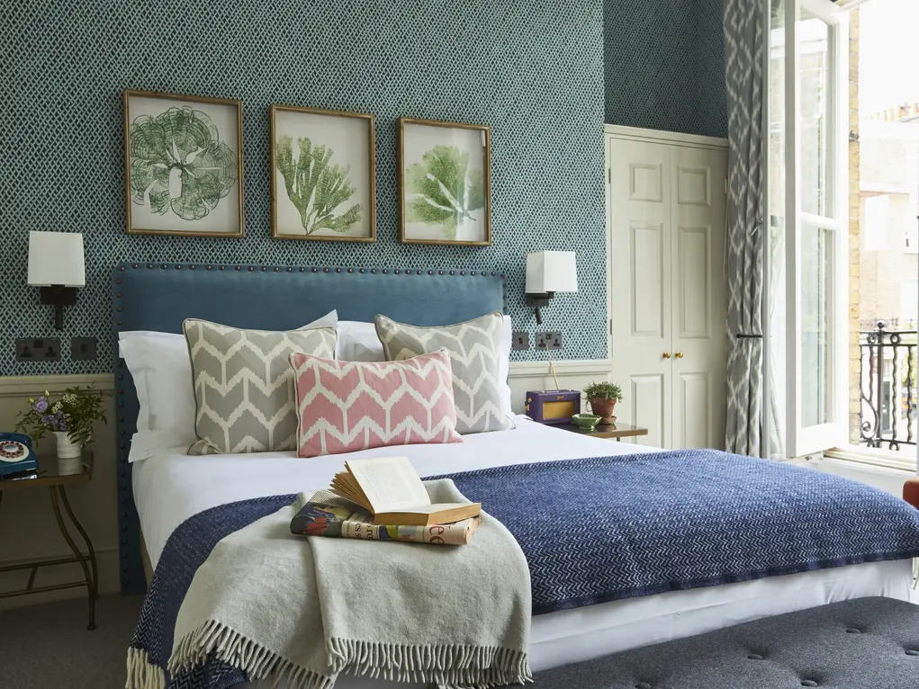 A hotel room with a bed and three botanical prints on the wall at the Lime Tree Hotel in Belgravia