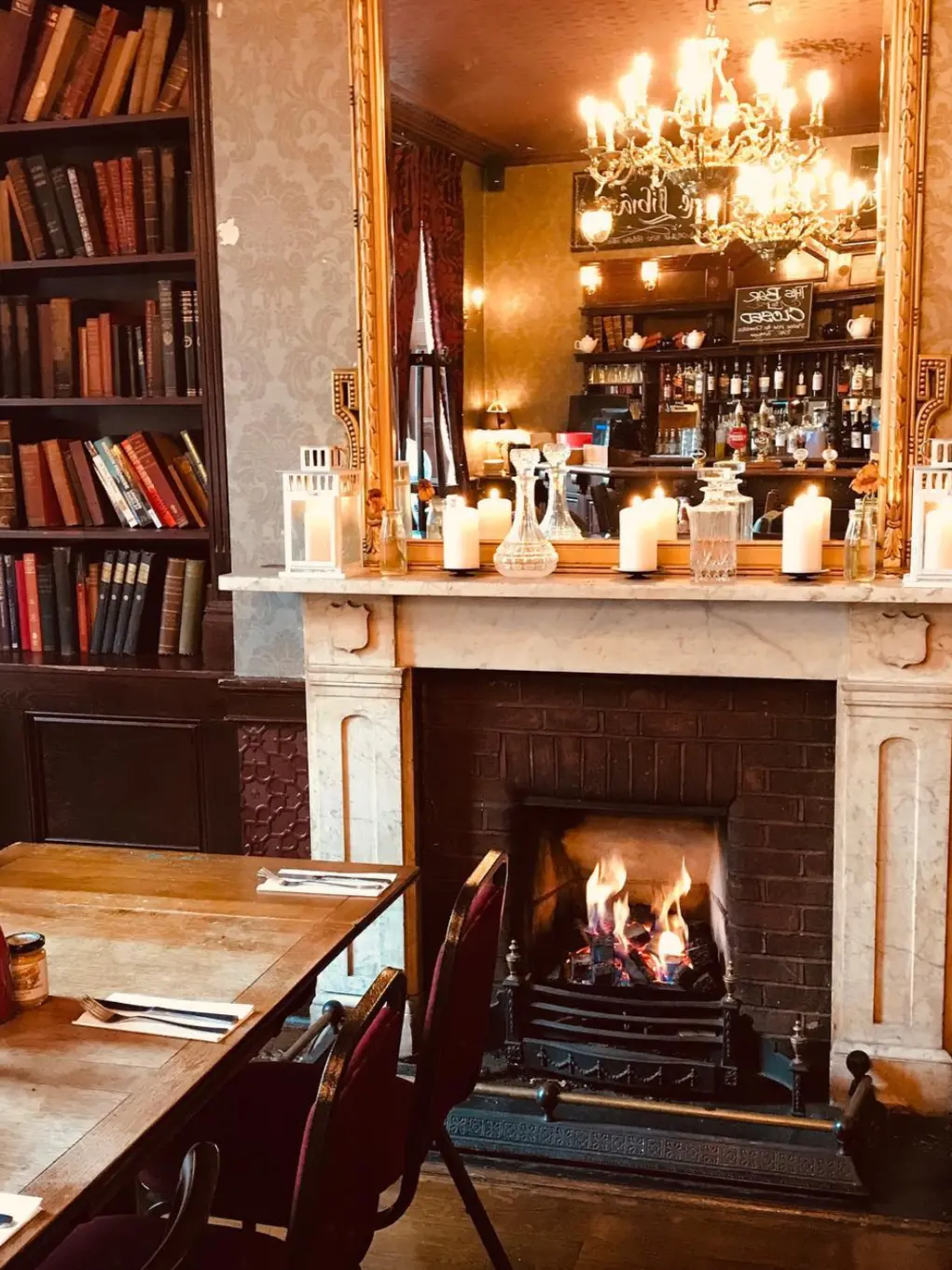 Wooden table in pub set for Sunday lunch in front of a open fire