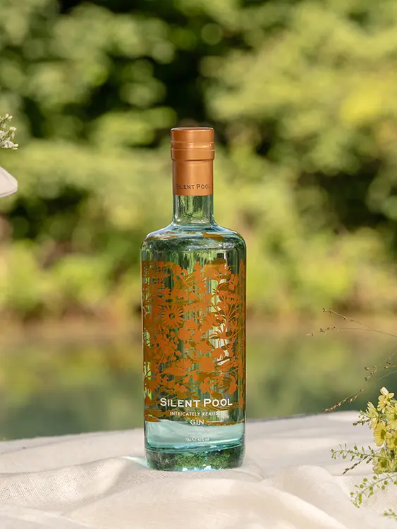 Bottle of Silent Pool gin on a table with flowers and a basket of flowers