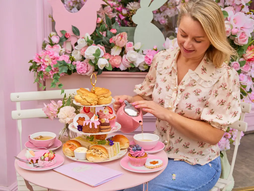 Peggy Porschen pouring a cup of tea next to a tiered cake tray